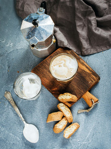 Glasses of coffee with ice cream on rustic wooden board steel Italian Moka pot over grey concrete textured background