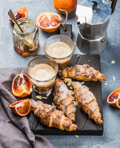 Traditional Italian style home breakfast  Latte in glasses  almond croissants and red bloody Sicilian oranges over concrete textured table