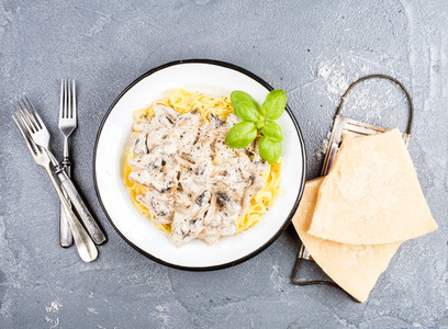 Tagliatelle pasta with mushrooms and creamy sauce parmesan cheese over concrete textured background