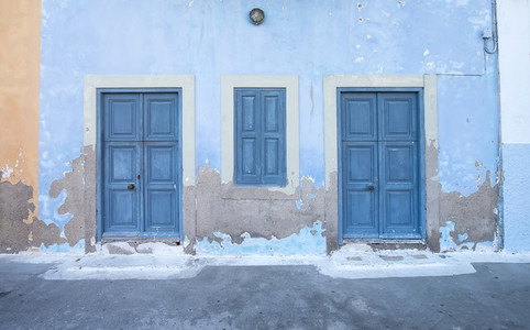 Mediterranean style exterior  Blue wooden doors and window shutters  old painted wall on a Greek island
