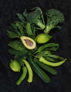Raw green vegetables set  Broccoli  avocado  pepper  spinach  zucchini  lime on dark stone background