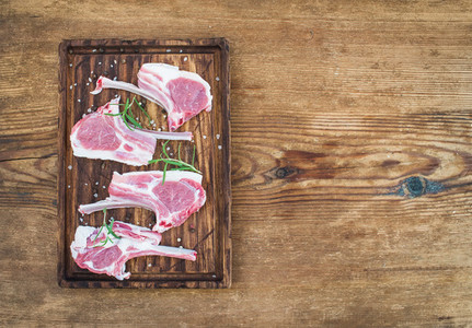 Rack of Lamb with rosemary and spices on rustic chopping board over old wooden background