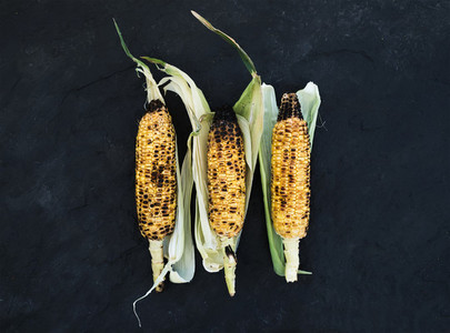 Grilled corn over black slate stone background top view