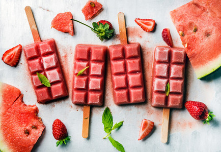 Strawberry watermelon ice cream popsicles with mint over steel tray background