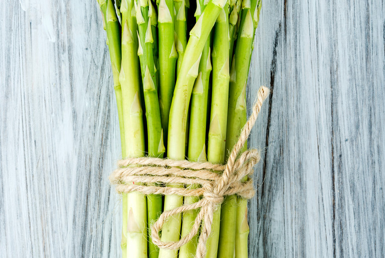 Green fresh asparagus on light painted wooden background