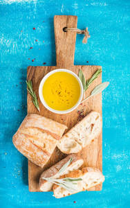 Mediterranean snacks set  Olive oil  herbs and sliced ciabatta bread on rustic wooden board