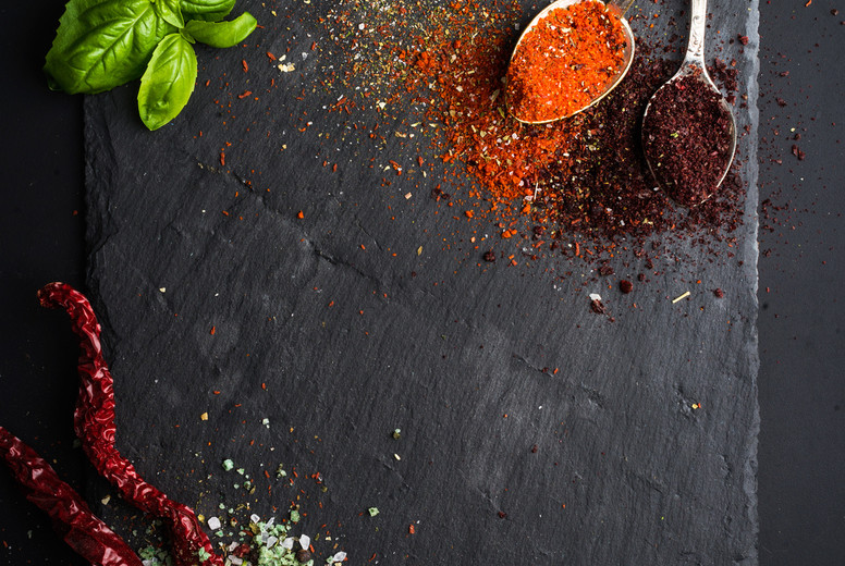 Herbs and spices on black slate stone board over dark background. 