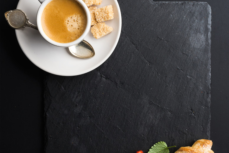 Espresso coffee cup and croissant with fresh strawberries on black  slate stone board over dark background