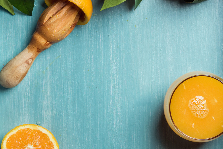 Fresh orange juice in glass and oranges with leaves on wooden turquoise blue painted background