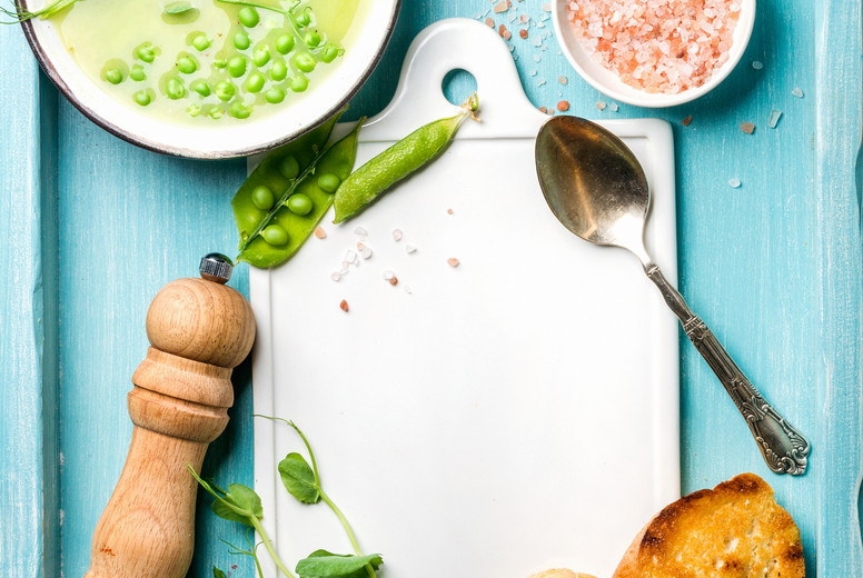 Light summer green pea cream soup in bowl with sprouts, bread toasts and spices. Top view, copy space