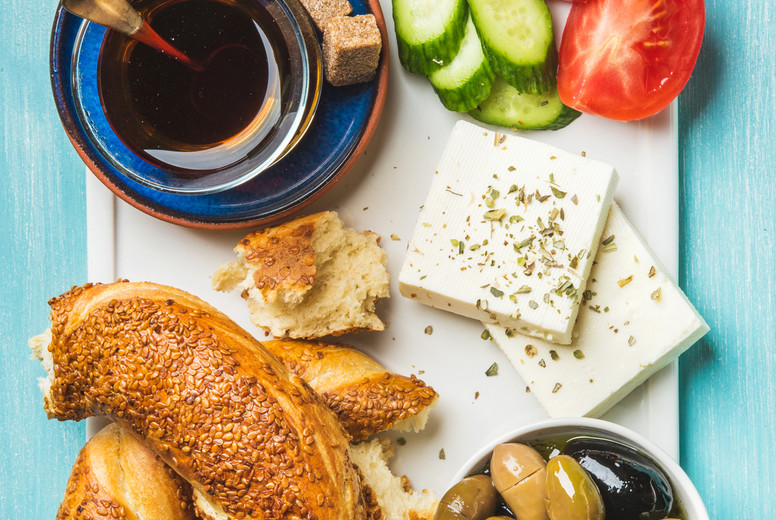 Turkish traditional breakfast with feta cheese, vegetables, olives, simit bagel and tea