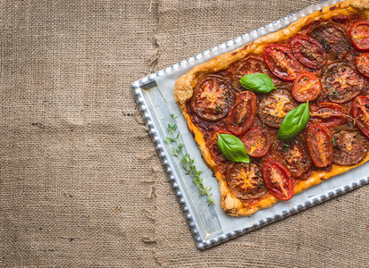 Rustic tomato autumn pie on a silver tray over a sackcloth surfa