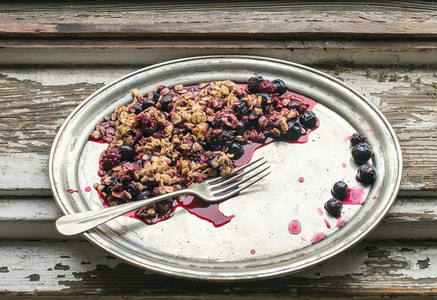 Oat granola with fresh berries on a silver dish with a fork over