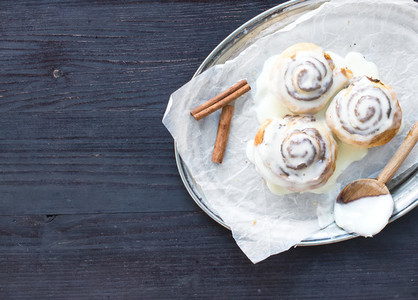 Cinnamon rolls with cream cheese icing and cinnamon sticks on a
