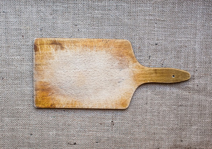 Rustic wooden cutting board over a sackcloth surface