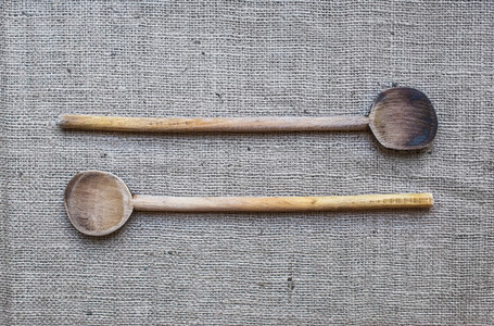 Two rustic wood cooking spoons over a sackcloth surface