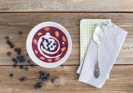 Blueberry and cream soup with almond over a rough wooden surface