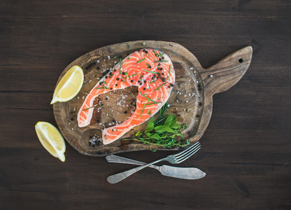 Raw salmon steak with fresh herbs  lemon and spices on rustic wo