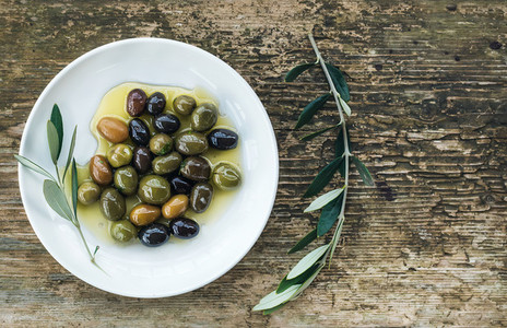 Plate of Mediterranean olives in oil with tree branch