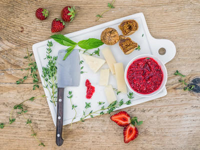 Cheese and fruit set on a white ceramic cutting board
