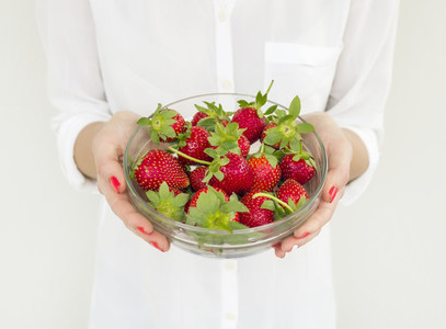 A bowl of strawberries in girl s hands