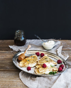 Thin pancakes or crepes with fresh raspberry cream mint on a
