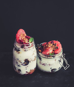 Yogurt and oat granola with grapes pomegranate grapefruit in tall glass jar