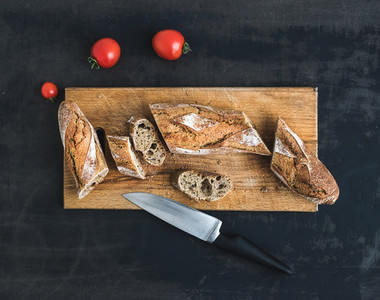 French baguette cut into pieces and cherry tomatoes on a rustic wooden board
