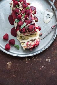 Semifreddo or italian cheese ice cream dessert with pistachios  fresh raspberries and mint on vintage silver tray over rusty grunge metal background  top view