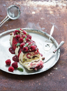 Semifreddo or italian cheese ice cream dessert with pistachios  fresh raspberries and mint on vintage silver tray over rusty grunge metal background  top view