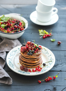 Breakfast set  Buckwheat pancakes with fresh berries and honey on rustic plate over black wooden table
