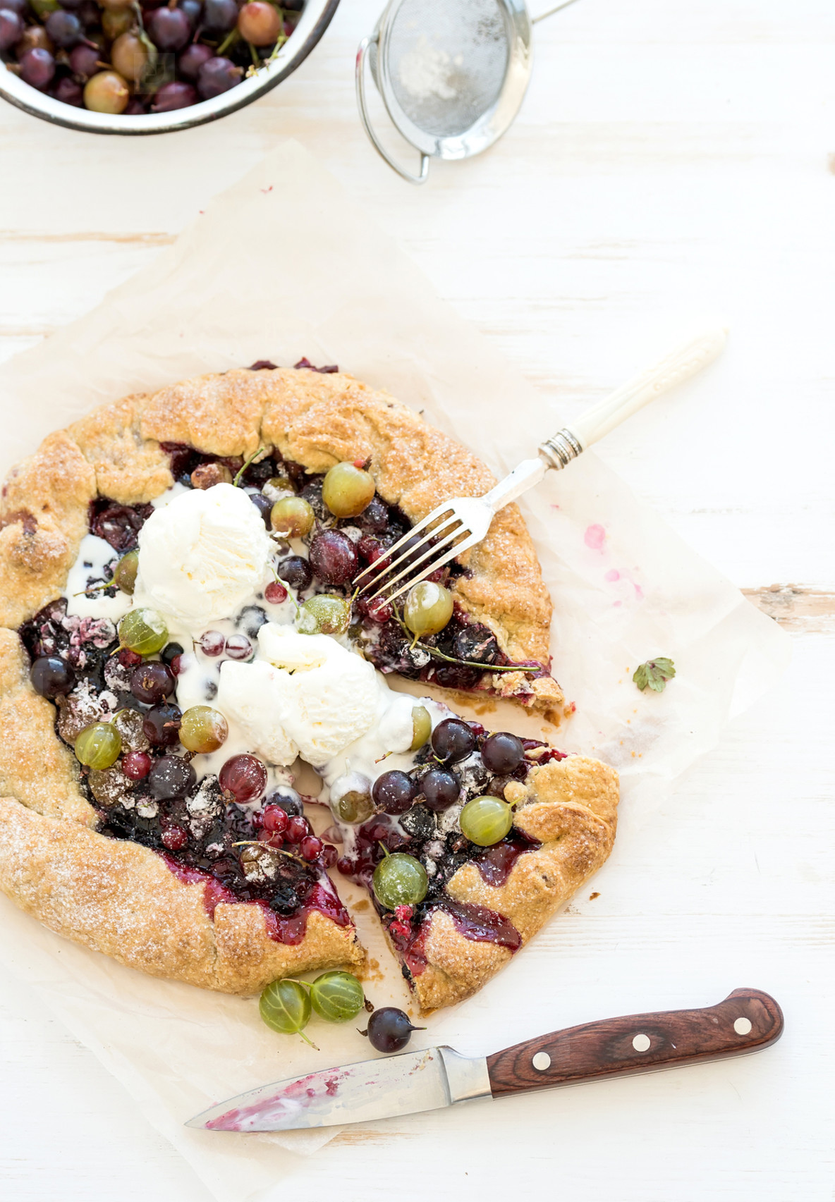 Summer crostata or galette pie with fresh garden berries and vanilla ice cream over white wooden background top view