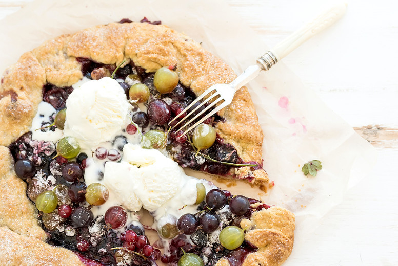 Summer crostata or galette pie with fresh garden berries and vanilla ice-cream over white wooden background, top view