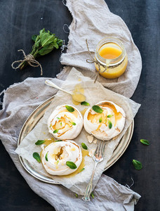 Merengues with lemon curd fresh mint on silver tray beige kitchen towel and grunge dark backdrop
