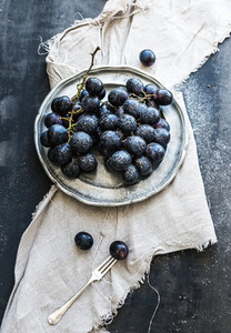 Bunch of fresh grapes in rustic vetal plate on dark grunge background