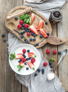 Healthy breakfast set Rice cereal or porridge with berries and honey over rustic wood backdrop