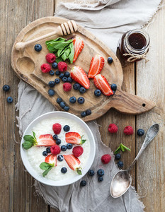 Healthy breakfast set  Rice cereal or porridge with berries and honey over rustic wood backdrop