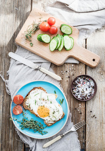 Breakfast set  Whole grain andwich with fried egg  vegetables and herbs on rustic wooden table  morning mood