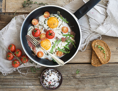 Pan of fried eggs  bacon and cherry tomatoes with bread