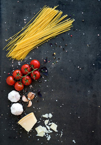 Food frame  Pasta ingredients  Cherry tomatoes  spaghetti pasta  garlic  basil  parmesan and spices on dark grunge backdrop  copy space