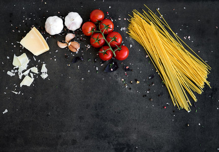 Food frame  Pasta ingredients  Cherry tomatoes  spaghetti pasta  garlic  basil  parmesan and spices on dark grunge backdrop  copy space  horizontal oriented
