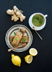 Cup of herbal tea with fresh mint  honey  lemon  ginger on grunge black  background