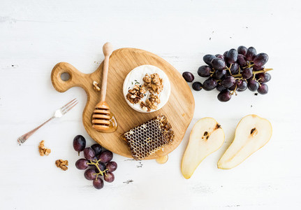 Camembert cheese with grape walnuts pear and honey on oak serving board