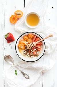 Healthy breakfast set  Rice cereal or porridge with fresh strawberry  apricots  almond and honey over white rustic wood backdrop  top view