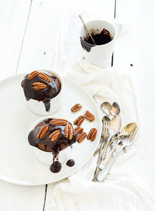 Tasty homemade brown muffins with chocolate ganache icing and pecan nuts in separate bakind cups