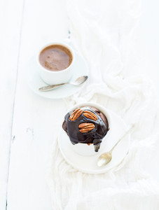 Tasty homemade brown muffin with chocolate ganache icing pecan nuts and coffee in separate bakind cup