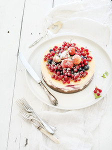 Cheesecake with fresh garden berries on top over white wooden table surface  Selective focus