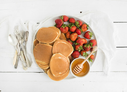 Breakfast plate Homemade pancakes with fresh strawberry and honey kitchen napkin vintage silverware on rustic white background Top view