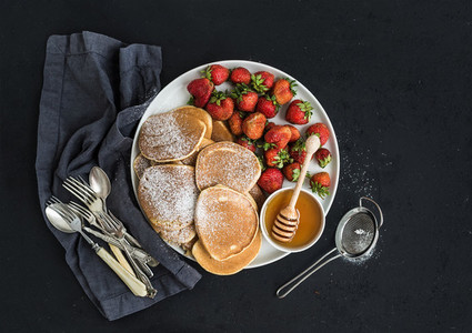 Breakfast plate  Homemade pancakes with fresh strawberry and honey  kitchen napkin  vintage silverware on dark grunge background  Top view