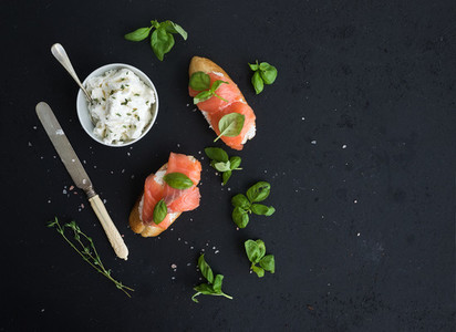 Salmon  ricotta and basil sandwiches over black grunge background  Top view
